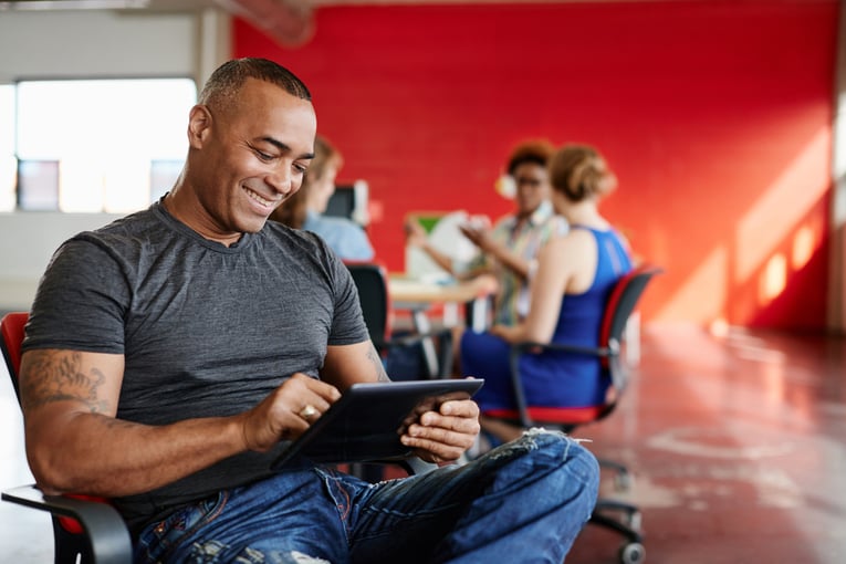 Confident male designer working on a digital tablet in red creative office space